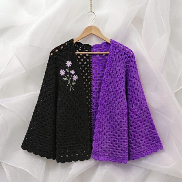 Black and purple crochet open shrug with embroidered lavender flowers on a hanger