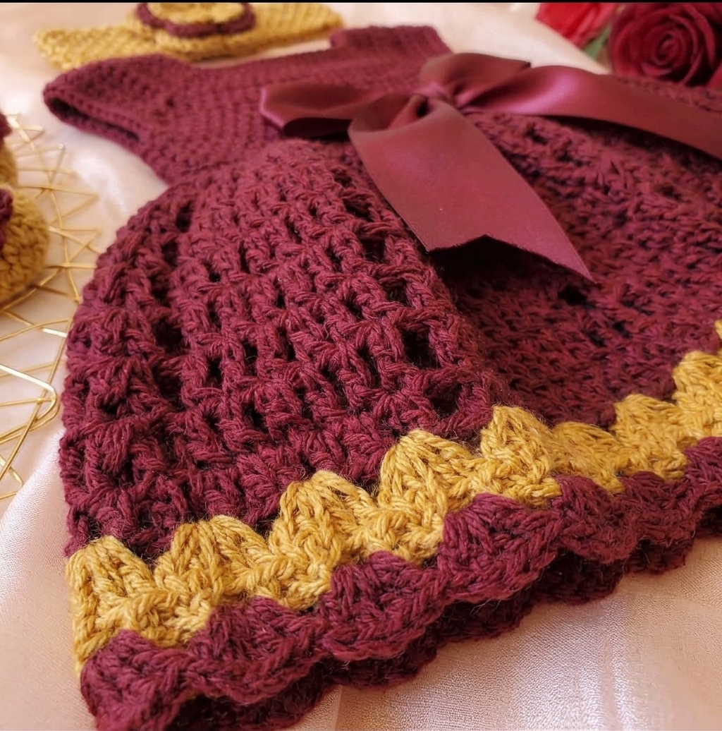 Close-up of mustard zigzag border on maroon crochet baby dress